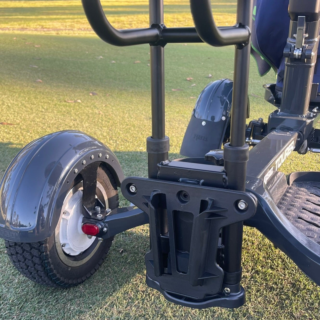Close-up of a golf cart's wheel and suspension system on grass